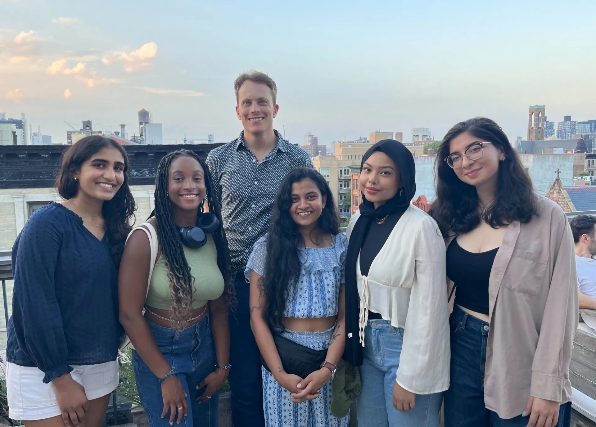 Six people posing for a photograph on a rooftop terrace in New York. 
