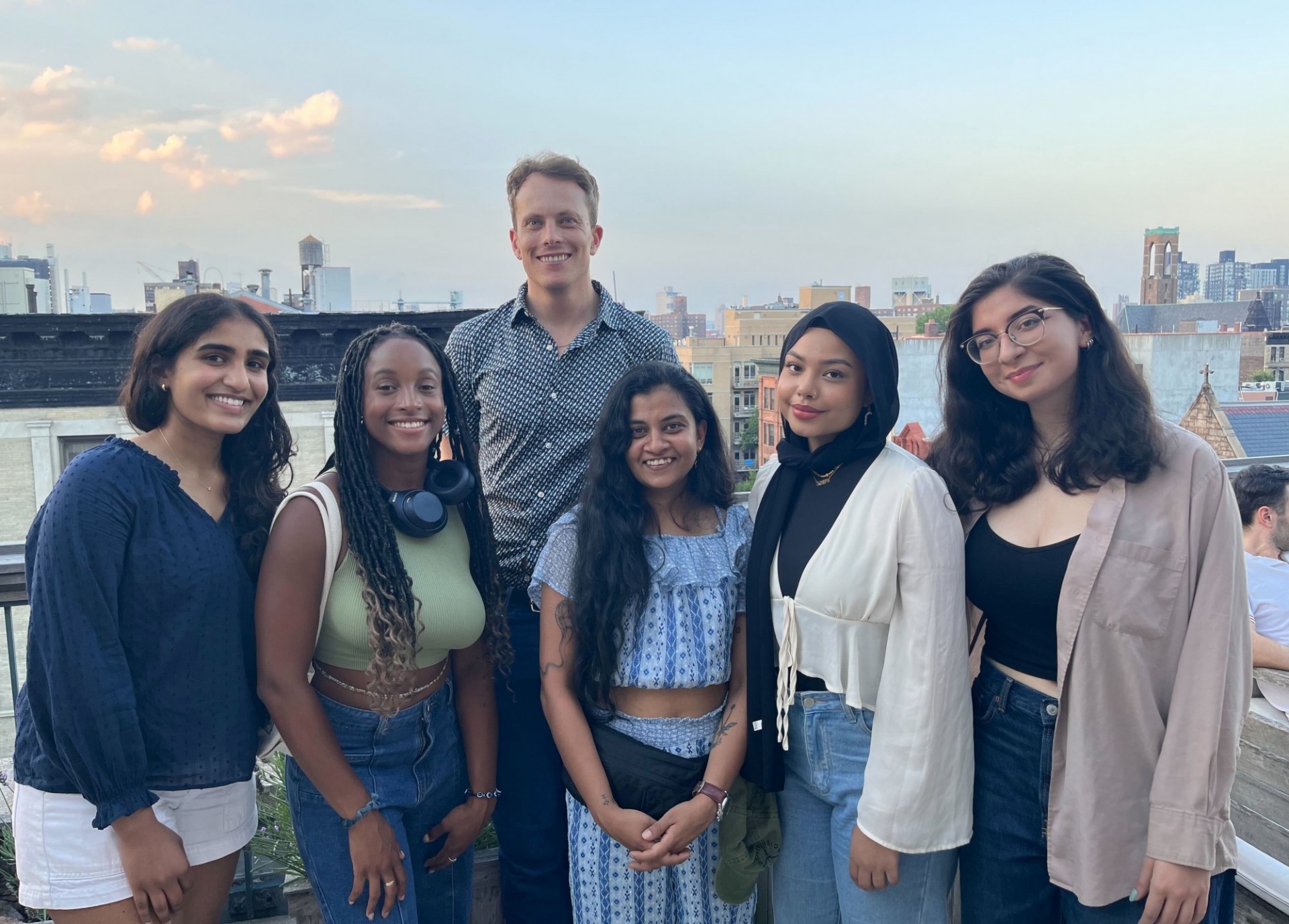 Six people posing for a photograph on a rooftop terrace in New York. 